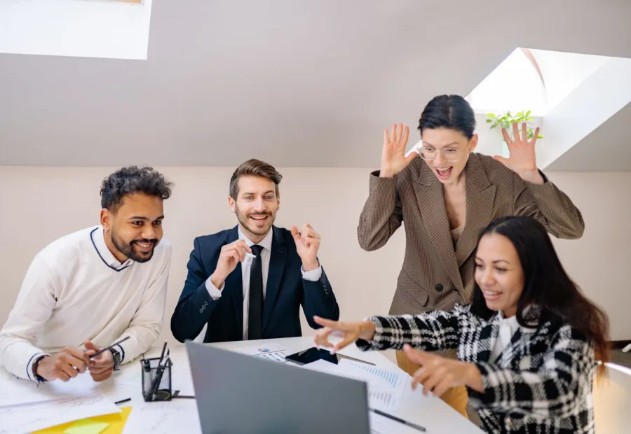 Team celebrating good results at a laptop