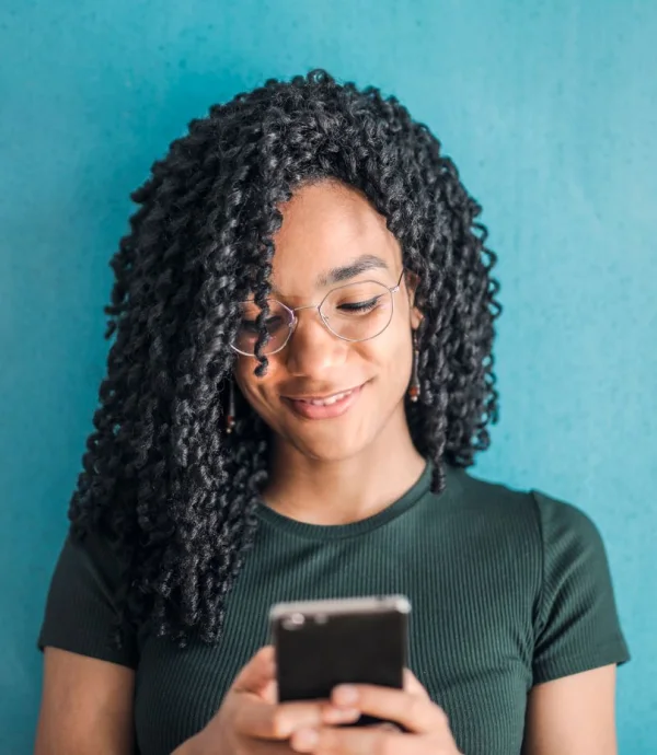 Smiling young woman with glasses using her phone