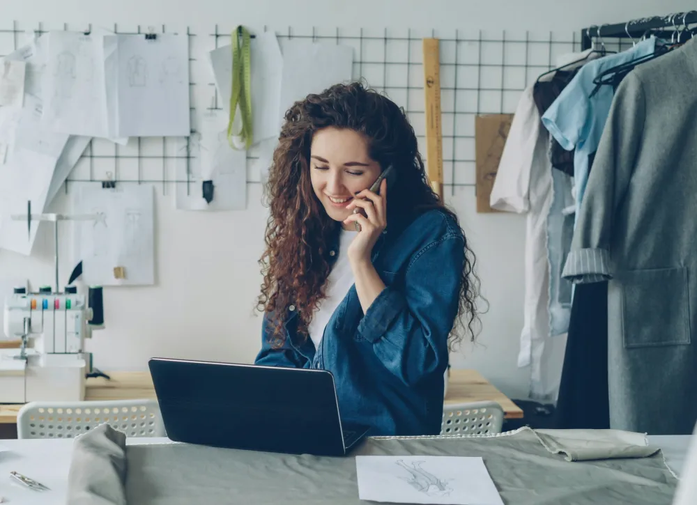 Small business owner on a call while working on her laptop in her studio
